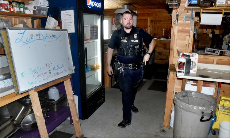 Skowhegan police officer Jake Boudreau inspects the kitchen area of the Skowhegan Lions Club food booth while he and officer Tim Williams search for evidence after a break-in and theft was discovered Sunday at the Skowhegan Fairgrounds site.