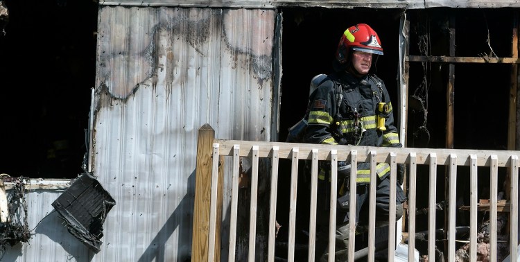Captain Douglas Ebert of the Farmingdale Fire Department emerges Monday from a mobile home that burned in Randolph. An occupant of the single-wide was taken to the hospital.