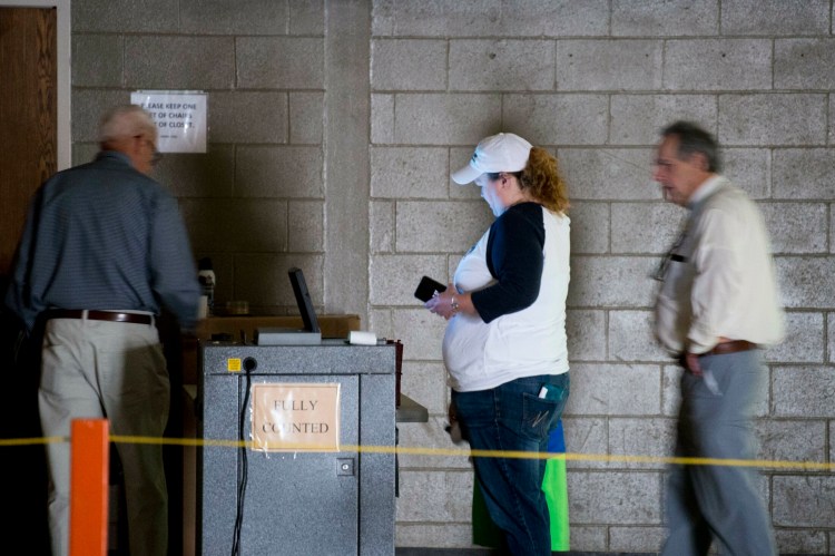 Volunteers and voters work in the dark to cast ballots Tuesday after a power outage at a voting station at the Fairfield Community Building. The School Administrative District 49 school district budget was on the ballot. 