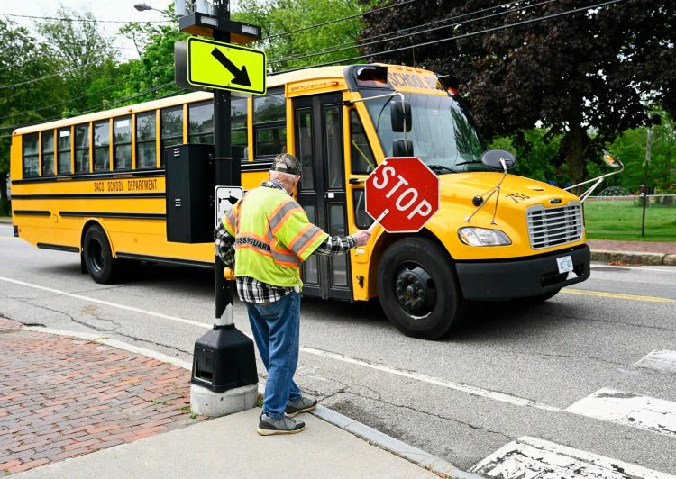 Homer Grant waves to a passing school bus on Friday, his last day as a crossing guard.