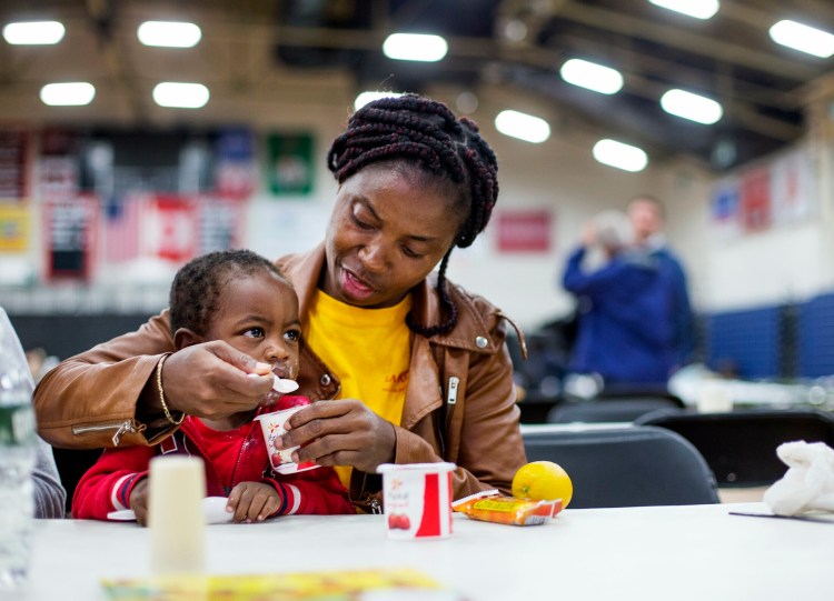 An asylum seeker from Cameroon, who did not want to give her name, feeds her son on June 13 at the emergency shelter the city has set up for asylum seekers at the Portland Expo. 