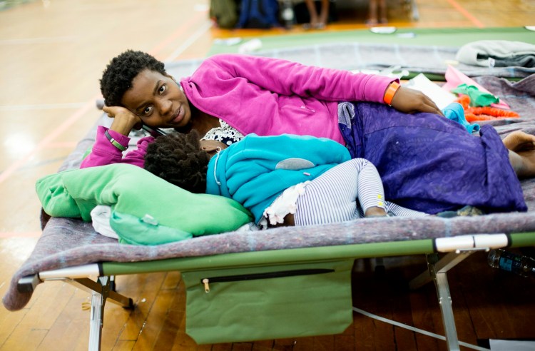 Sofia Ida of the Democratic Republic of the Congo rests with one of her children at an emergency shelter for asylum seekers at the Portland Expo. Ida, who is pregnant, came to Portland with her two children and her husband after fleeing from the Congo to Brazil. 