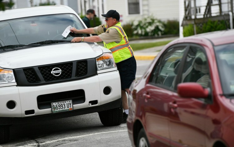 A parking enforcement officer places a ticket on a vehicle parked on Washington Street in downtown Biddeford in June. 