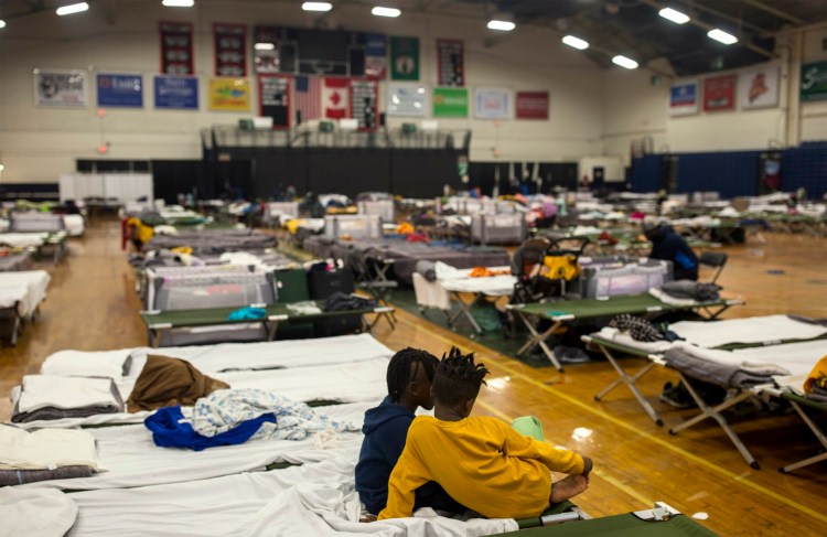 Two children sit on one of the cots set up for asylum seekers in the emergency shelter at the Portland Expo on JUne 19.