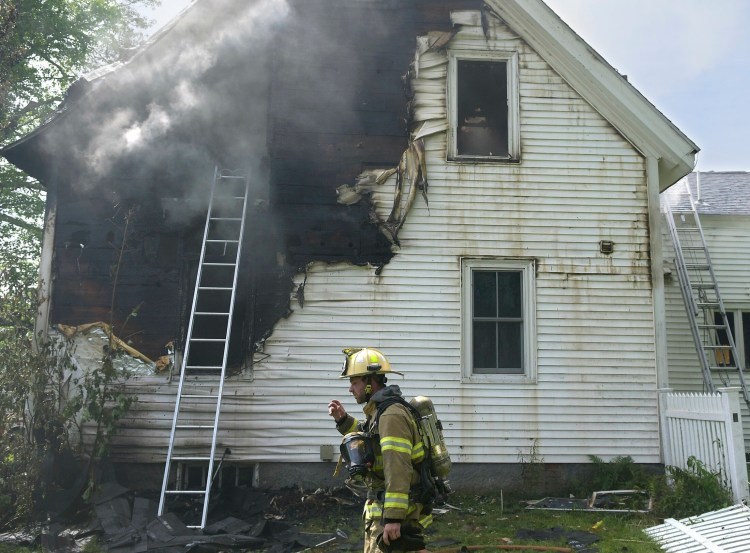 A firefighters surveys a house that was damaged by fire Tuesday on Prescott Road in Manchester.