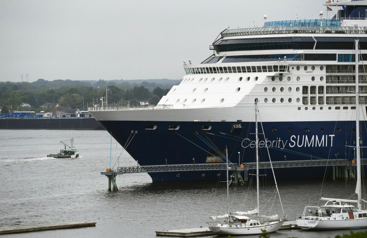 A lobster boat motors past the cruise ship Celebrity Summit, docked in Portland Harbor in June 2019. A full schedule of cruise ships will return to Maine this summer following a two-year hiatus.