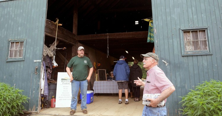 Corey O'Connell, left, speaks Sunday with customer Jim Grenier at the Briggs Farm in Somerville.