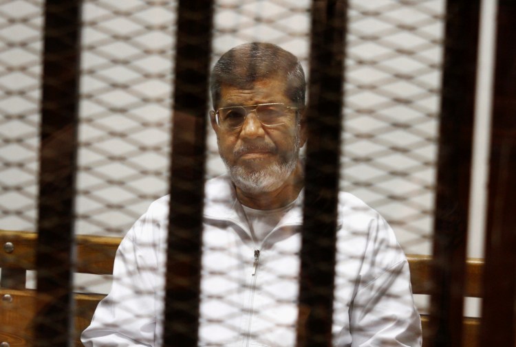 Egypt's ousted Islamist President Mohammed Morsi sits in a defendant cage in the Police Academy courthouse in Cairo in 2014. On Monday, Egypt's state TV said Morsi, 67, collapsed and died while he was attending a court trial on espionage charges.