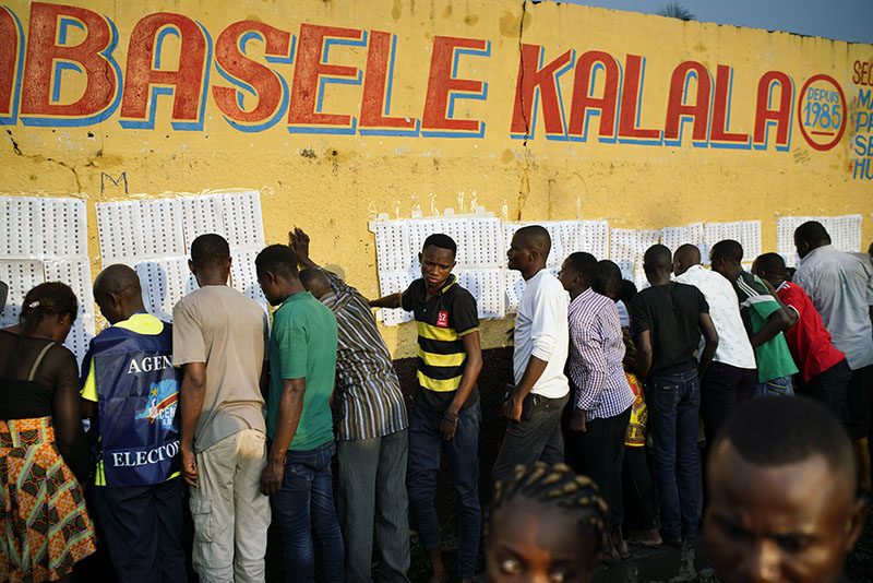 Election officials tape voter registration lists to a wall of the Les Anges primary school in Kinshasa, Congo, as voters start to check their names, Sunday Dec. 30, 2018. The election process was delayed when voters burned six voting machines and ballots midday, angered by the fact that the registrations lists had not arrived. Replacement machines had to be brought in, and voting started at nightfall, 12 hours late. Forty million voters are registered for a presidential race plagued by years of delay and persistent rumors of lack of preparation. Associated Press/Jerome Delay