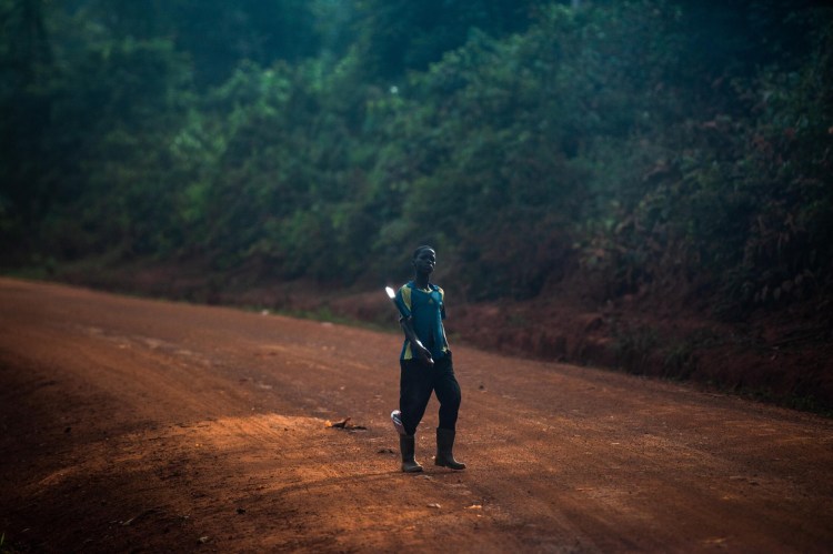 A boy holds his machete as he heads along a road to a cocoa farm. 