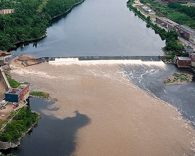 The Kennebec River is clouded with dirt and silt as the rushing waters from the upper section of the river flow freely through the breach (at left) in Edwards Dam in July 1999.