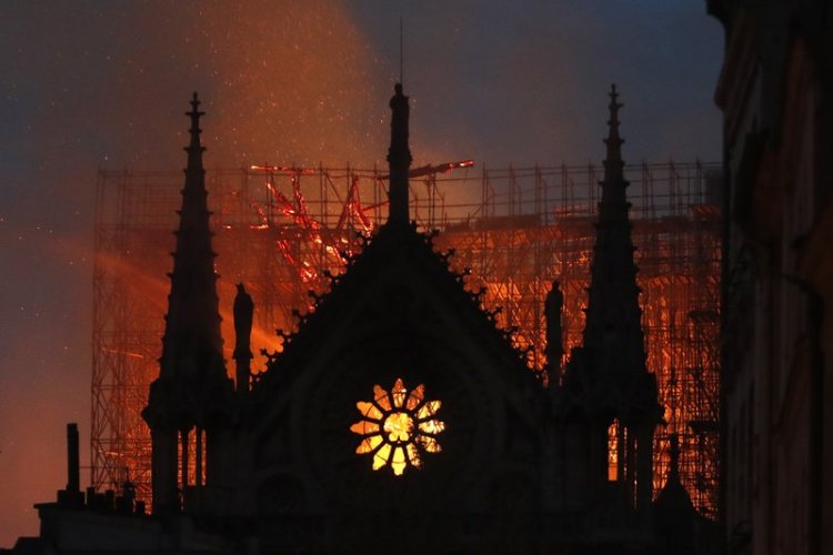 Flames and smoke rise from Notre Dame cathedral as it burns in Paris, Monday, April 15, 2019. Massive plumes of yellow brown smoke filled the air above Notre Dame Cathedral and ash fell on tourists and others around the island that marks the center of Paris.