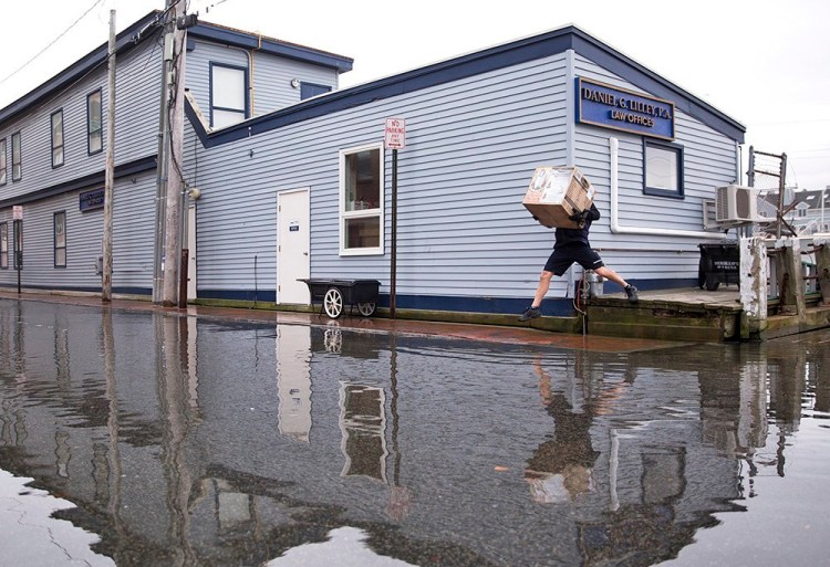 A FedEx delivery man jumps over pooling water on Portland Pier during a 2016 king tide. 