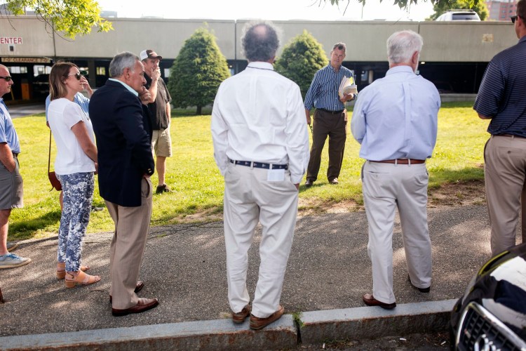 Attorney Jonathan Flagg, center, begins the bidding in a foreclosure auction for a strip of land in Portland in front of the Chestnut Street Garage. Massachusetts-based developed Ted Moore bought both the Portland land and property on Saco Island on Tuesday.