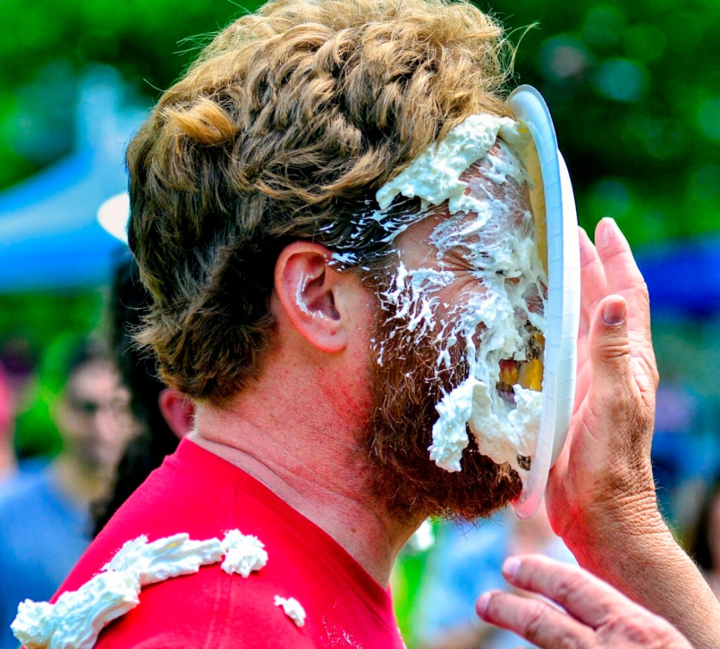 Chase Morrill, of the "Maine Cabin Masters" television show, gets hit in the face with a plate of whipped cream Saturday during the Strawberry Festival in Wayne. There was a raffle for a chance to hit a cast member with a pie. 