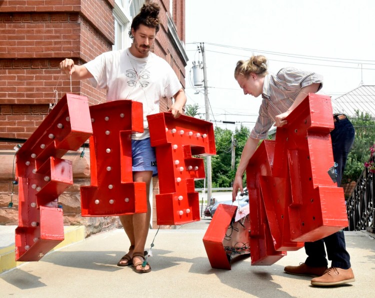 Aaron Canter, left, and Tom Crisp arrange large red letters that spell "MIFF," the acronym of the Maine International Film Festival. The letters will be erected at the Waterville Opera House. That is one of the venues where films will be shown during the 22nd annual festival.
