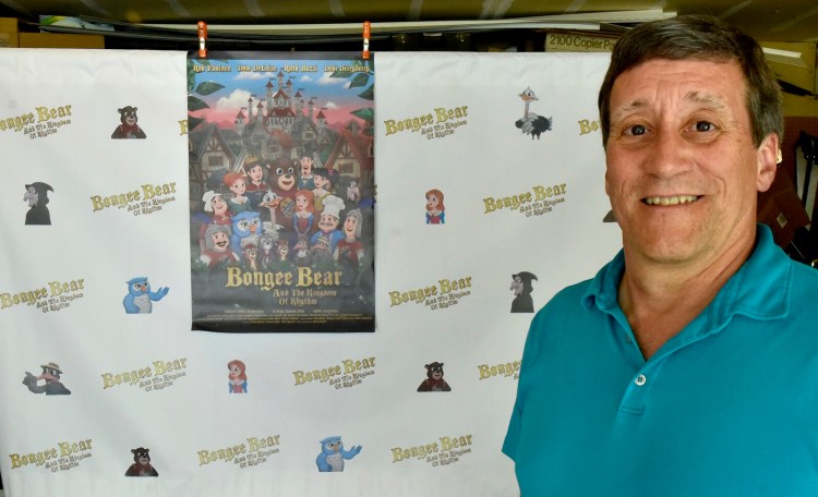 Filmmaker Brian Zemrak, of Winslow, poses on Thursday before a wall hanging and poster of his animated movie, "Bongee Bear and the Kingdom of Rhythm." The movie will premiere Saturday during the Maine International Film Festival.