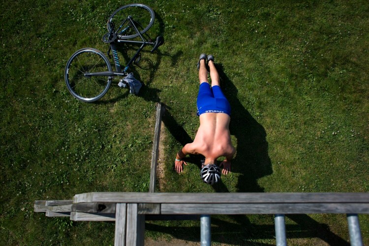 Mateo Hodo of Portland does exercises after riding his bike to Back Cove on Monday. He said that the heat doesn't bother him, and that he would be out doing the same thing if the temperature was in the nineties. 