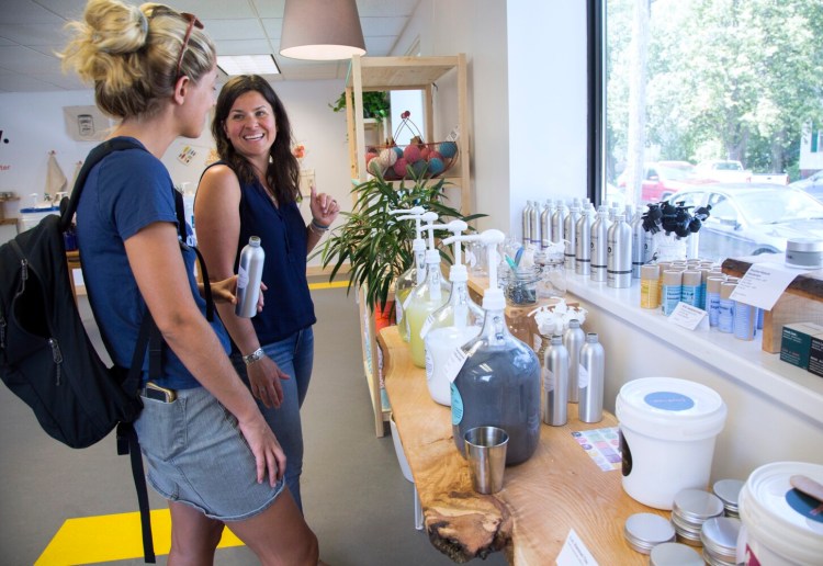 Laura Marston, center, owner of GoGo Refill, a store where customers can bring refillable containers to buy such products as laundry detergent, talks with Lexi Doudera, a customer who lives in the South Portland neighborhood. 