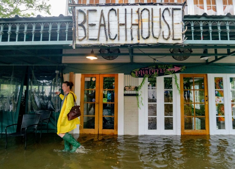 Aimee Cutter, the owner of the Beach House restaurant, walks through a storm surge from Lake Pontchartrain on Lakeshore Drive in Mandeville, La., on Saturday.

