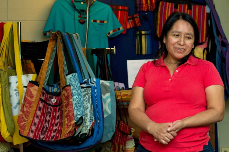 Maria Chavalan-Sut of Guatemala stands next to items she has made at the Wesley Memorial United Methodist Church in Charlottesville, Va. She uses fabric that a son has mailed to her from Guatemala to make a range of goods. She can’t sell them, but she accepts donations in exchange.