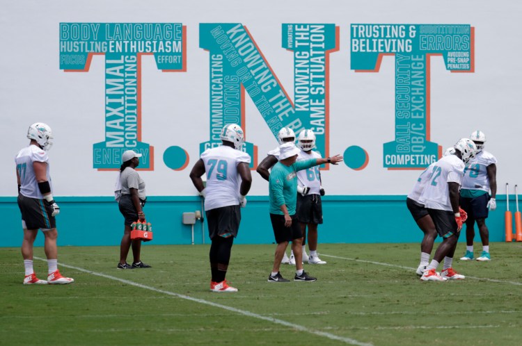 Dolphins offensive line coach Pat Flaherty, center, was fired by the team on Monday, just four practices into training camp. He has been replaced by Dave DeGuglielmo.
