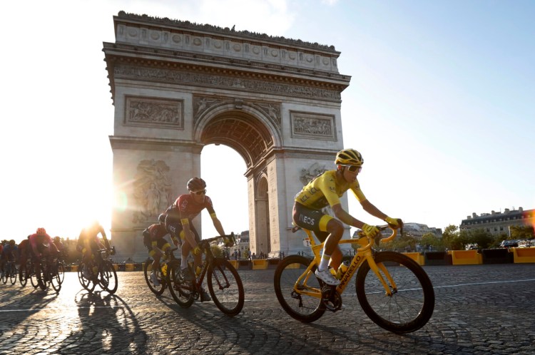 Colombia's Egan Bernal wearing the overall leader's yellow jersey, center, rides past the Arc de Triomphe on the Champs-Elysees during the final stage of the Tour de France on Sunday.