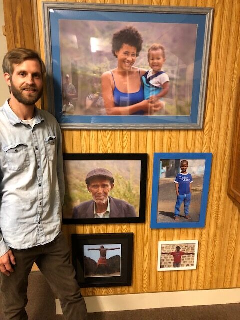 Caleb Baker, of Hallowell, stands on Saturday next to photos he shot during his travels in Cape Verde. The photos were displayed at Post Office Square in Waterville as part of the MIFFONEDGE Volume 7 event.
