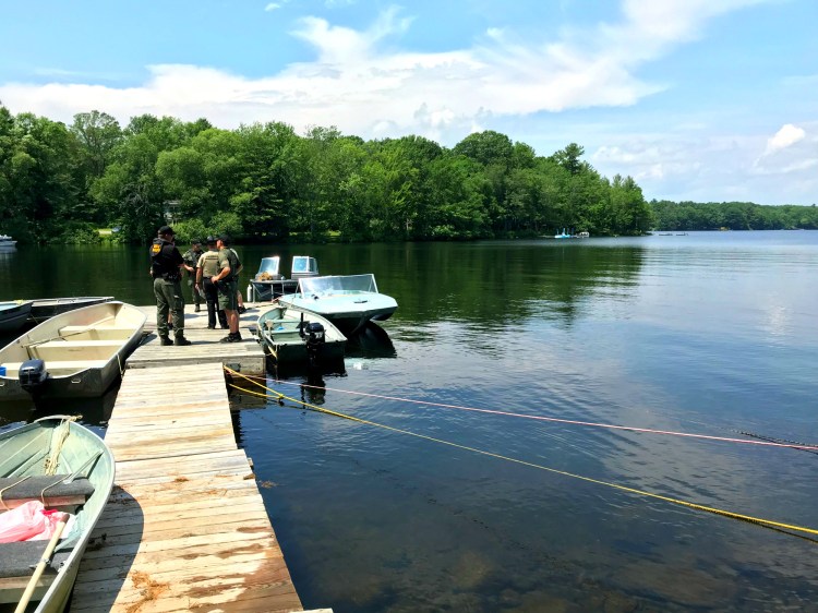 Officials from the Maine Warden Service and Kennebec County Sheriff's deputies stand on a dock near where Christopher Brown's body and boat were discovered Saturday morning. 