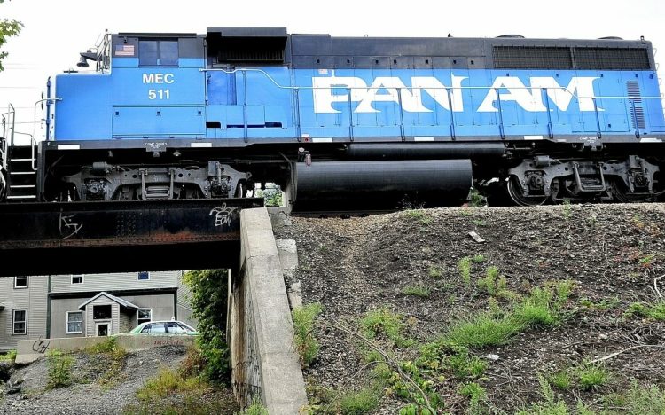 A Pan Am Railways engine pulls railroad cars over a trestle as cars pass below on Front Street in Waterville. The railway and state Department of Transportation are embarking on a $35 million upgrade of the freight line to improve safety and enhance business opportunities, especially with Maine's resurgent paper industry. 