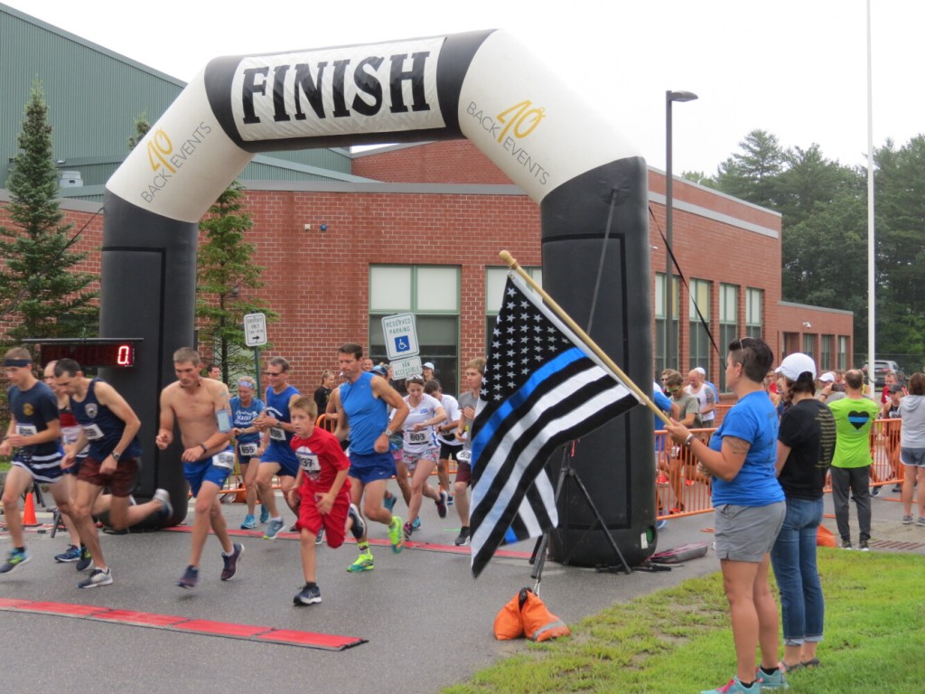 Samantha DeLorie, a planning committee member for the Corporal Cole Memorial 5K and Half Marathon, holds the flag Sunday as runners leave the starting line. 