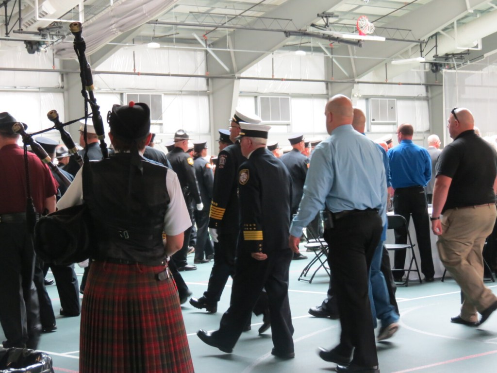 A lone bagpiper plays Sunday during the start of a celebration of life service for Fairfield Fire Capt. Jim Lane. At center are some of Lane's colleagues. 