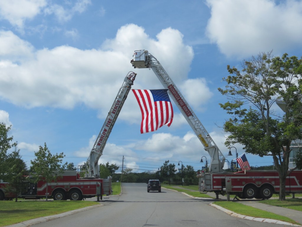 Waterville and Winslow Fire Departments raise a flag at the entrance to Thomas College to honor the late Fire Capt. Jim Lane on Sunday in Waterville.  