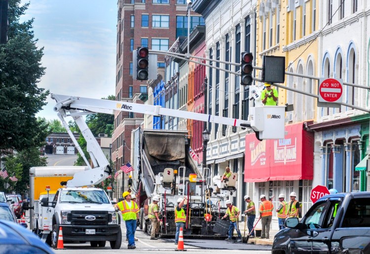 Construction workers pave the road at the corner of Water and Bridge streets Wednesday in downtown Augusta. When the work is completed Monday afternoon, Water Street will be open to two-way traffic.