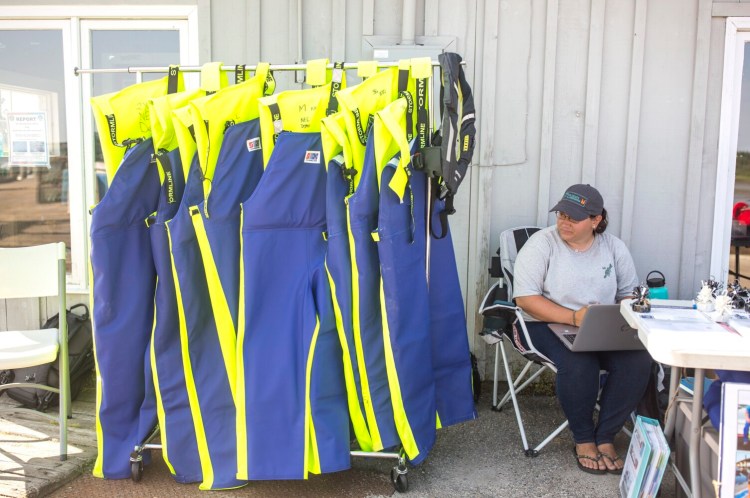 Mandy Roome, a field research coordinator with the Northeast Center for Occupational Health and Safety, sells lifejackets customized for lobstermen on the Cape Porpoise Pier on Thursday. Since April 1, the organization has sold 450 lifejackets, with the coveralls containing flotation devices the most popular option, according to Roome. The group is working its way up the Maine coast, selling a variety of lifejackets at a discount to Maine lobstermen.