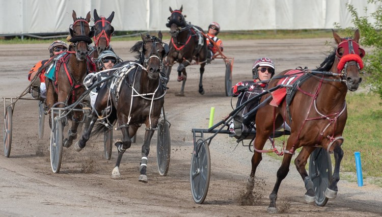 Jockeys open up around the final turn during a harness race at the 2019 Topsham Fair. 