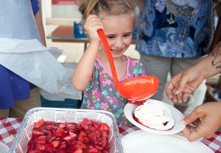 Adrea Jones, 5, ladles a helping of strawberry shortcake at the Oak Grove Center tent with the help of Erika Semones, right, at the 2019 annual Taste of Waterville on Main Street in downtown Waterville.