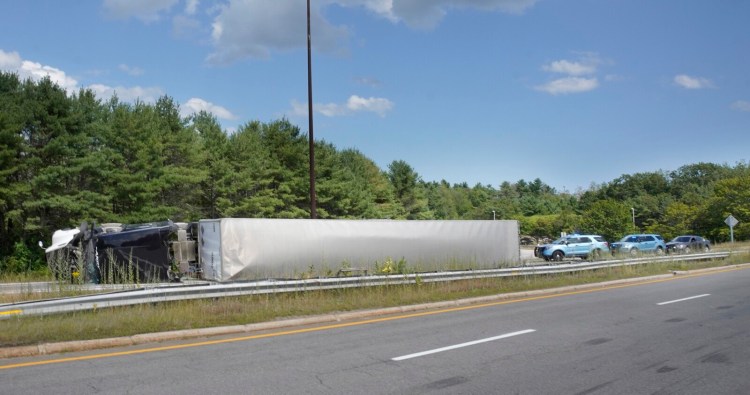 A tractor-trailer rests on its side after rolling over at the on-ramp to the Falmouth Spur of the Maine Turnpike from Interstate 295 southbound in Falmouth on Friday.