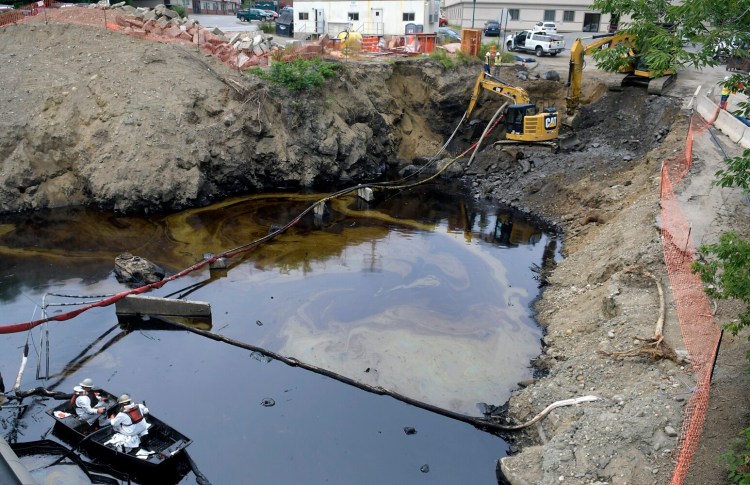 Workers clean oil Tuesday from a pit on Arcade Street in Gardiner.