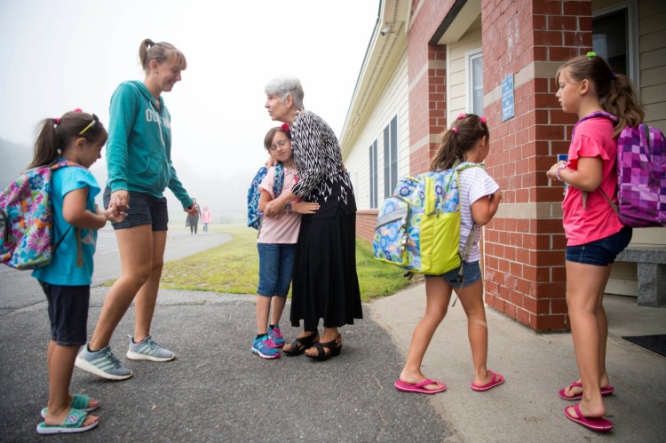 Helen Peavey gives a hug to Kylie Savage on Wednesday, the first day of school at Madison Elementary School. Peavey, a special ed paraprofessional, greets students arriving to school every day.