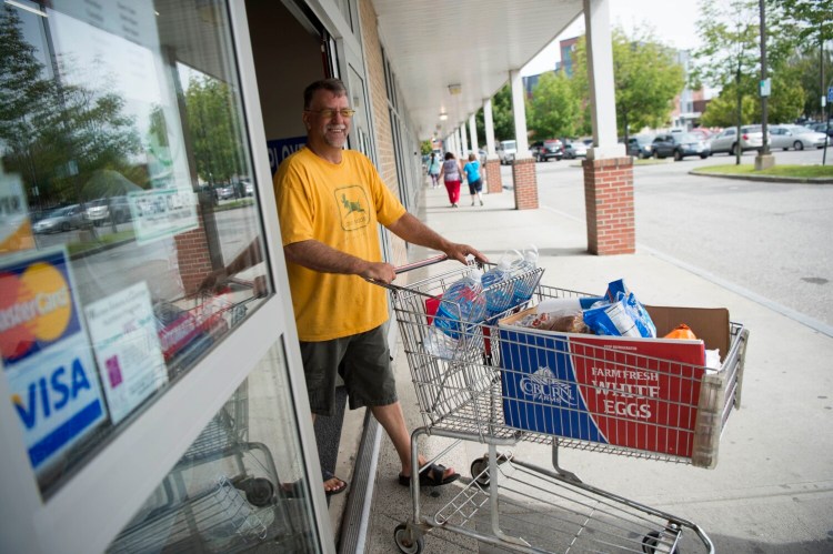 Bruce Palmer heads out of Save-A-Lot at The Concourse in downtown Waterville on Thursday with his boxed groceries. 