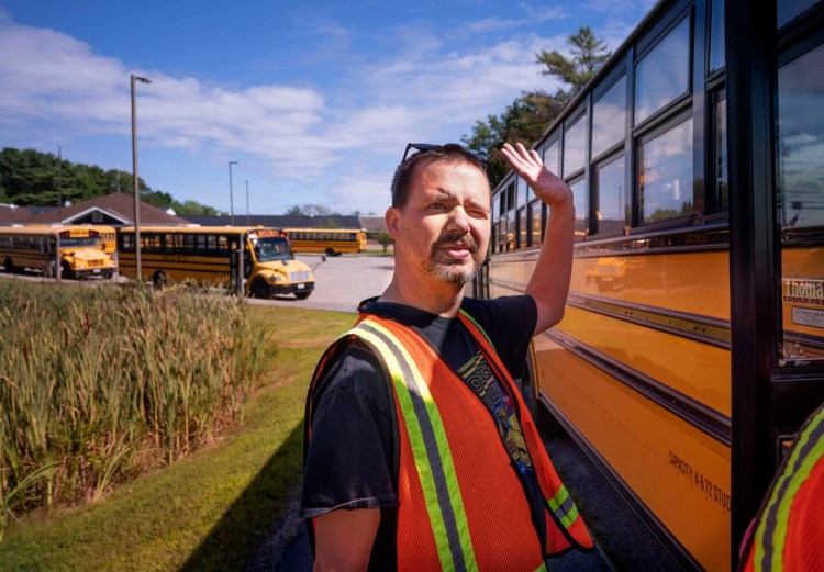 Joshua Strong waves to a passer-by while waiting for buses to leave on Wednesday at Great Salt Bay Community School in Damariscotta, where he works as a traffic guard in the afternoons.