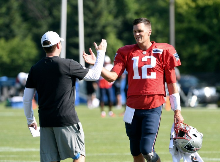 Detroit General Manager Bob Quinn, left, greets Patriots quarterback Tom Brady as the teams practiced together Monday in Allen Park, Mich.