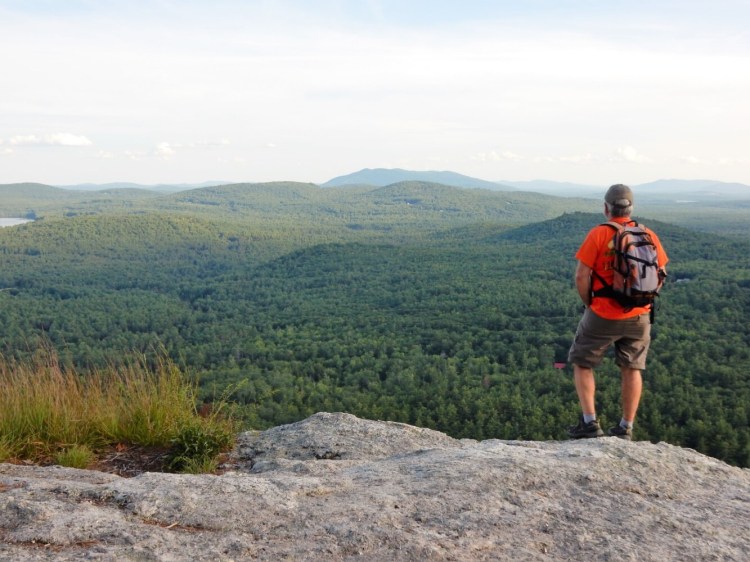 Carey Kish takes in the view of Pleasant Mountain from atop the sweeping cliffs on Sabattus Mountain. 