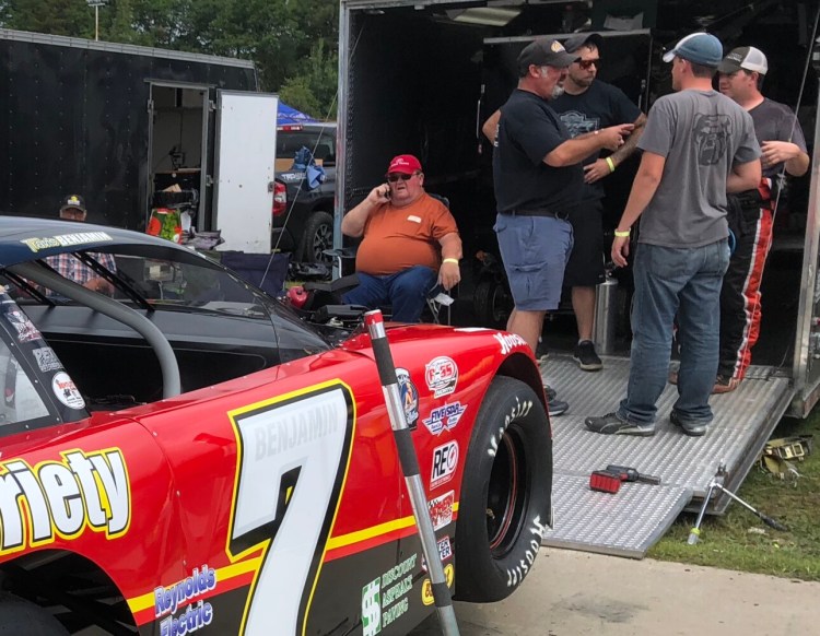 Ron Benjamin, seated left, and Travis Benjamin, far right, over see their team's pit area during practice Saturday for the 46th annual Oxford 250 at Oxford Plains Speedway. 