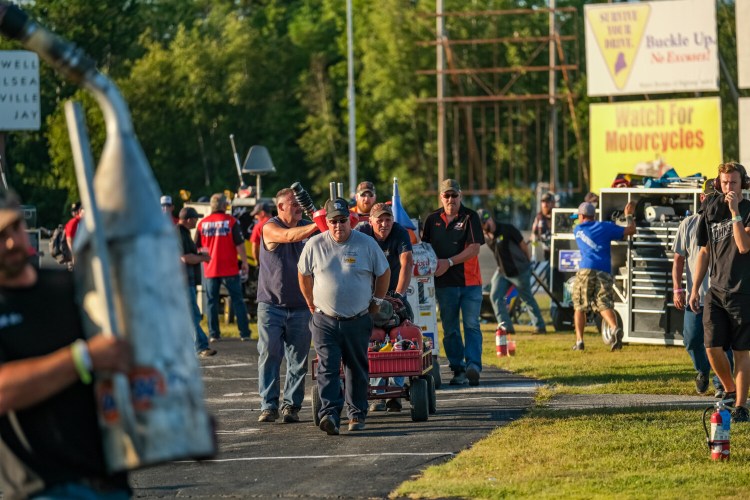 Pit crews bring their equipment onto the infield to prepare for the 46th annual Oxford 250 last summer. Crews will be limited for Sunday's season opener and no fans will be allowed to attend.