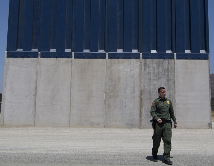 A Border Patrol official inspects border wall prototypes in the San Diego area in April 2018. 