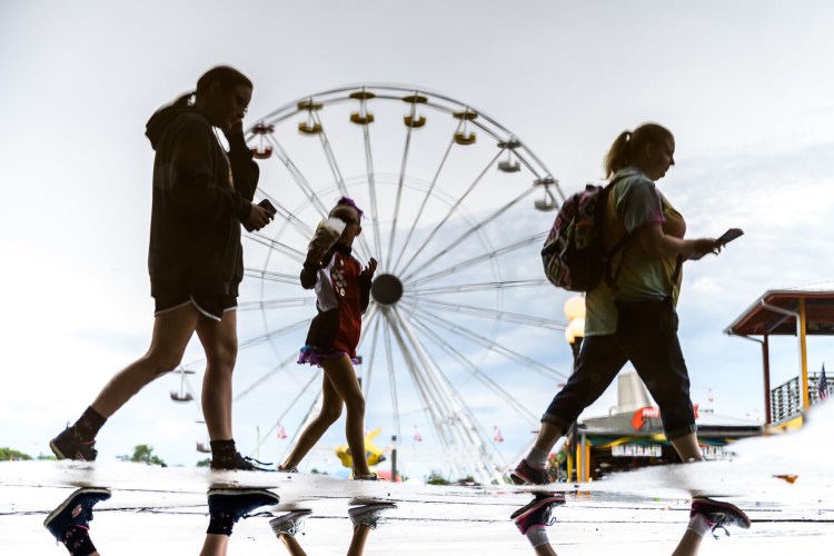 Visitors trek through the Iowa State Fair during rainy conditions Aug. 12 in Des Moines.