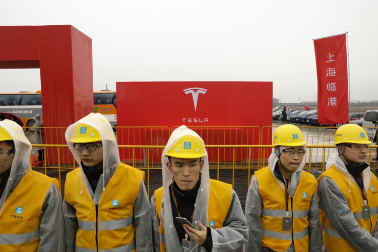 Workers in rain gear wait ahead of an event at a Tesla manufacturing facility in Shanghai in January. White House economic director Larry Kudlow and Treasury Secretary Steven Mnuchin both confirmed President Trump has the authority to force American companies to leave China but that there is no indication he'll invoke the law.