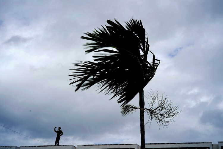 A man stands on a store's roof as he works to prepare it for the arrival of Hurricane Dorian in Freeport on Grand Bahama, Bahamas, on Sunday. 